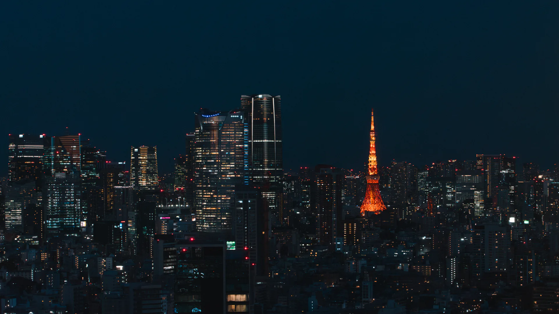 Tokyo Tower illuminated within the Minato skyline at night.